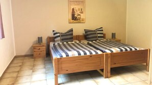 A double bed with striped bedding, two bedside tables, and a wall-mounted artwork. - Ferienwohnung am Schöneberg Nähe Nürburgring (Heckenbach)
