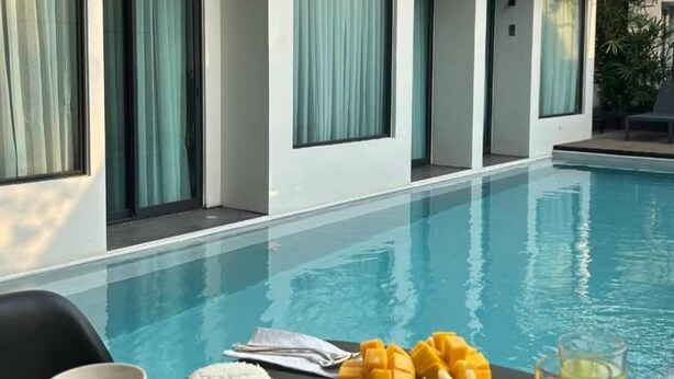 A dining table with a meal by a poolside, including a cup, plates of food, and a glass of juice. - POR Arak (Chiang Mai)