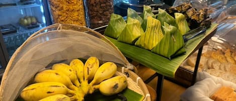 A display of bananas, tamales, and a basket of bread in a food section.