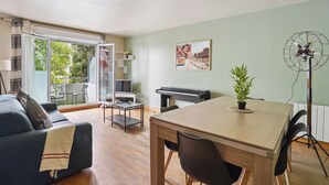 Una sala de estar moderna con un sofá, una mesa de comedor, un piano y un ventilador.