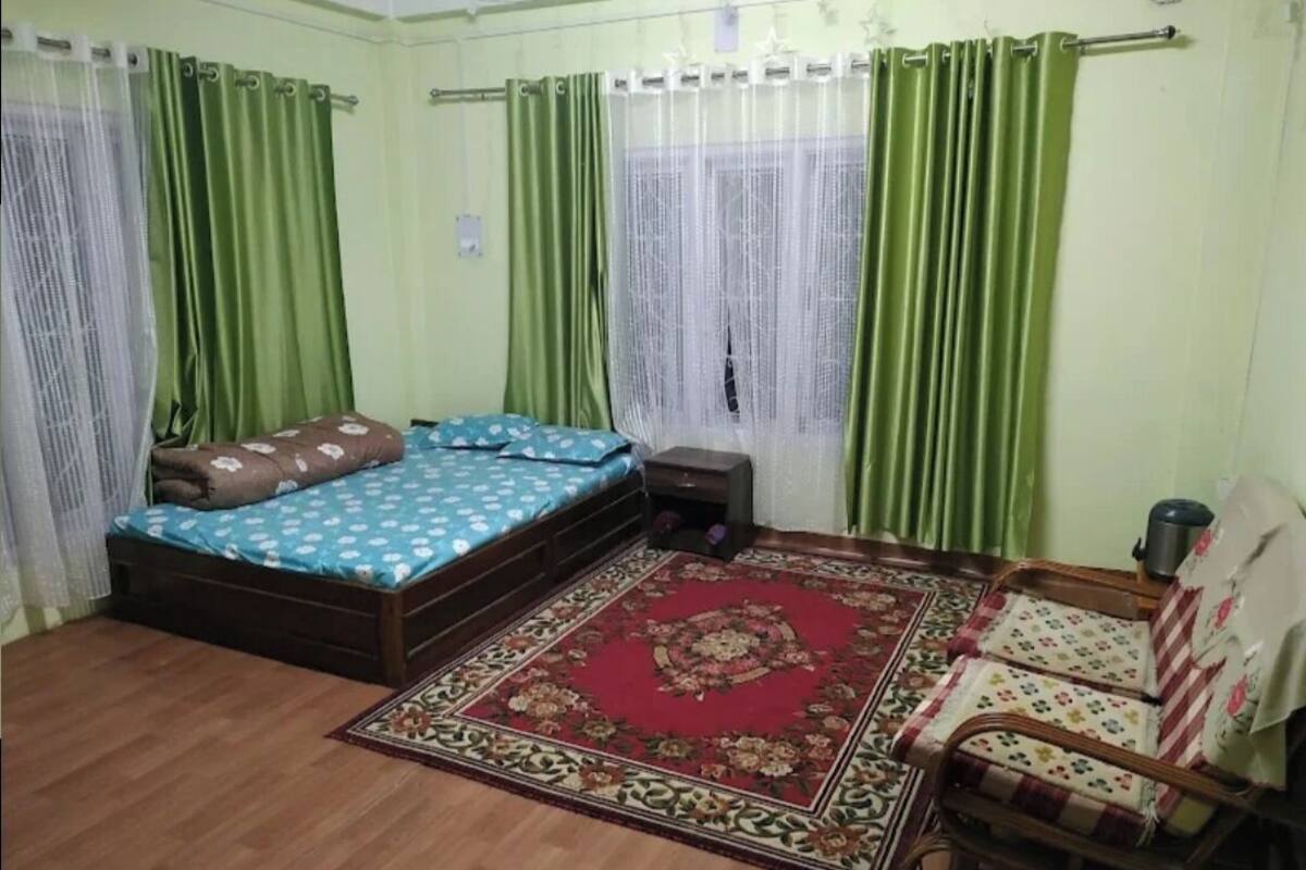 A bedroom with a bed, a chair, a small table, and a decorative rug.