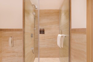 A modern shower with a glass door, a handheld showerhead, and a towel rack.