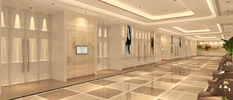 A spacious hotel lobby with a polished marble floor, a reception desk, and a seating area with chairs and a table.