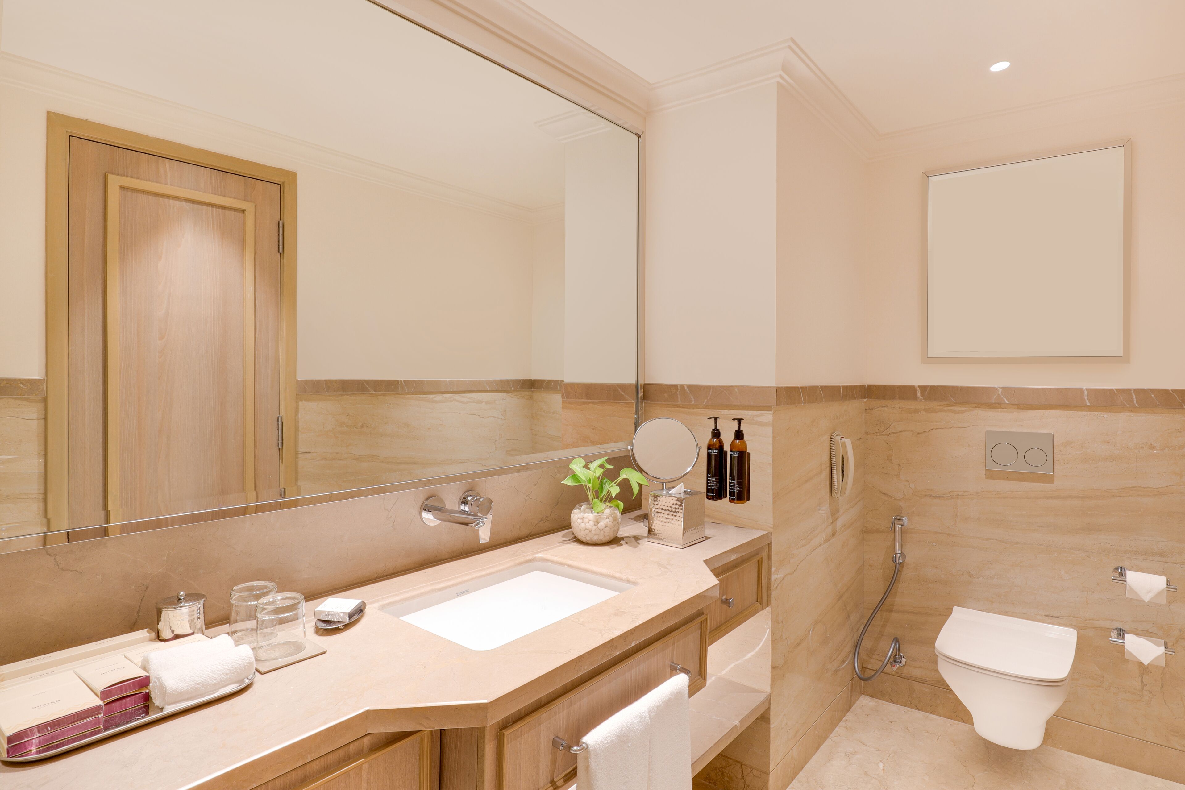 A modern bathroom with a large mirror, a sink, a toilet, and a shower.