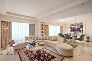 A spacious living room with a curved sofa, a coffee table, and a dining area with chairs and a table.