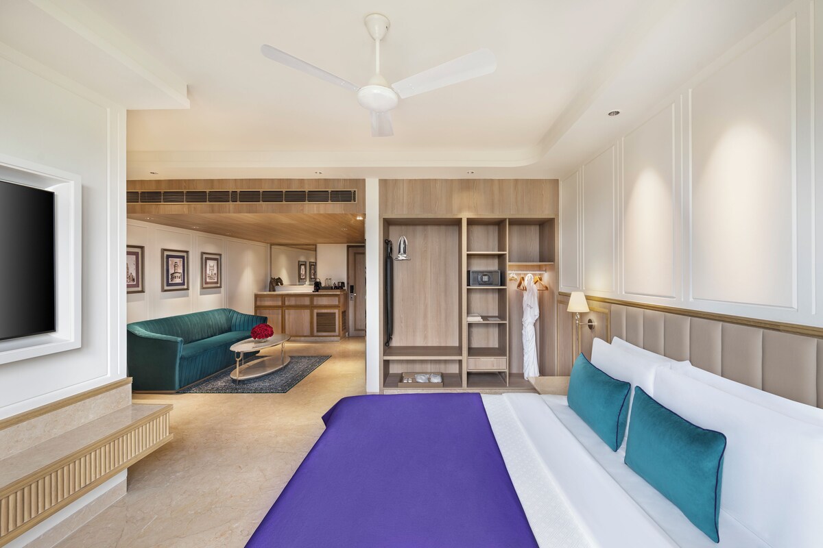 Een moderne hotelkamer met een groot bed, een zithoek met een bank, een televisie en een kitchenette.