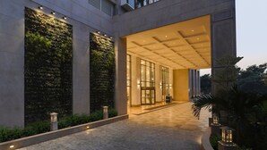 Una entrada de edificio moderna con puerta de vidrio, piso de baldosas y un jardín vertical a la izquierda.