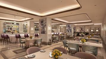 A modern hotel lobby with a bar, dining area, and seating.