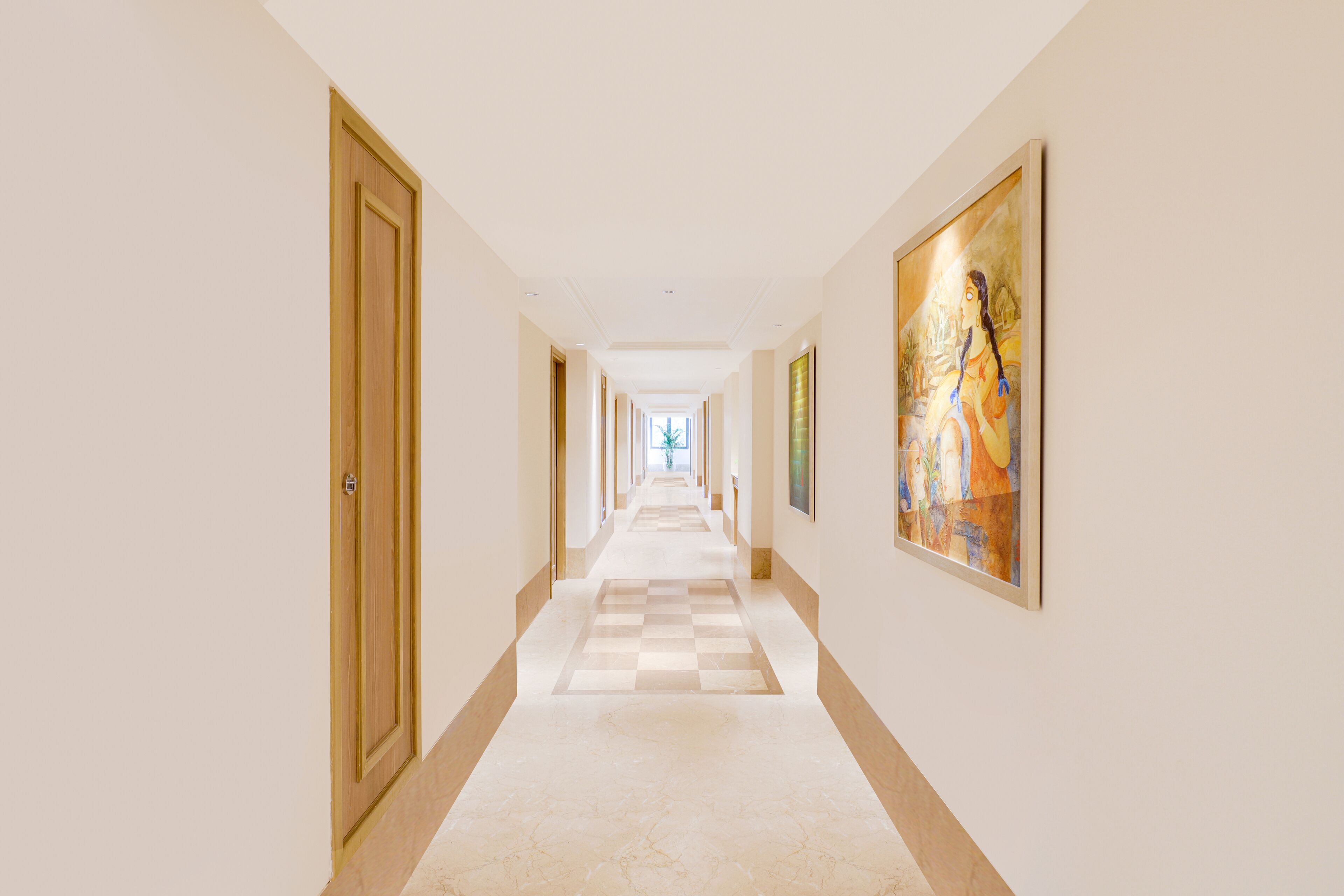 A hotel hallway with a checkered floor, wooden doors, and framed artwork on the walls.