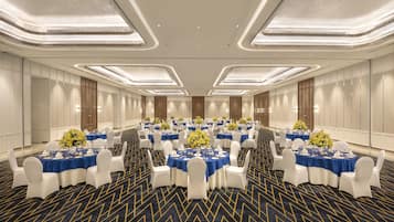 A large conference room with round tables, white chairs, and blue tablecloths.