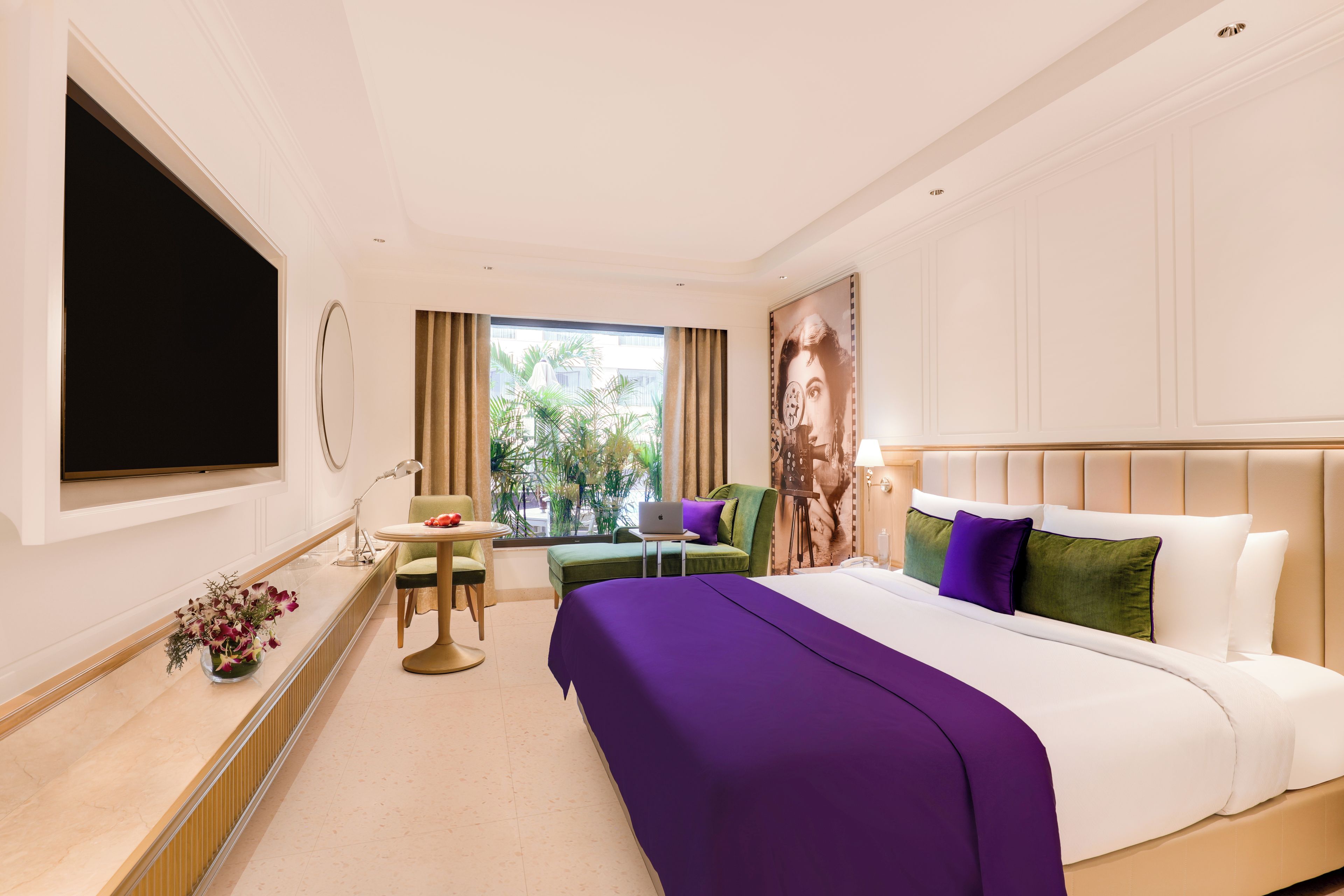 A hotel room with a bed, a desk, a chair, a TV, and a window with curtains.