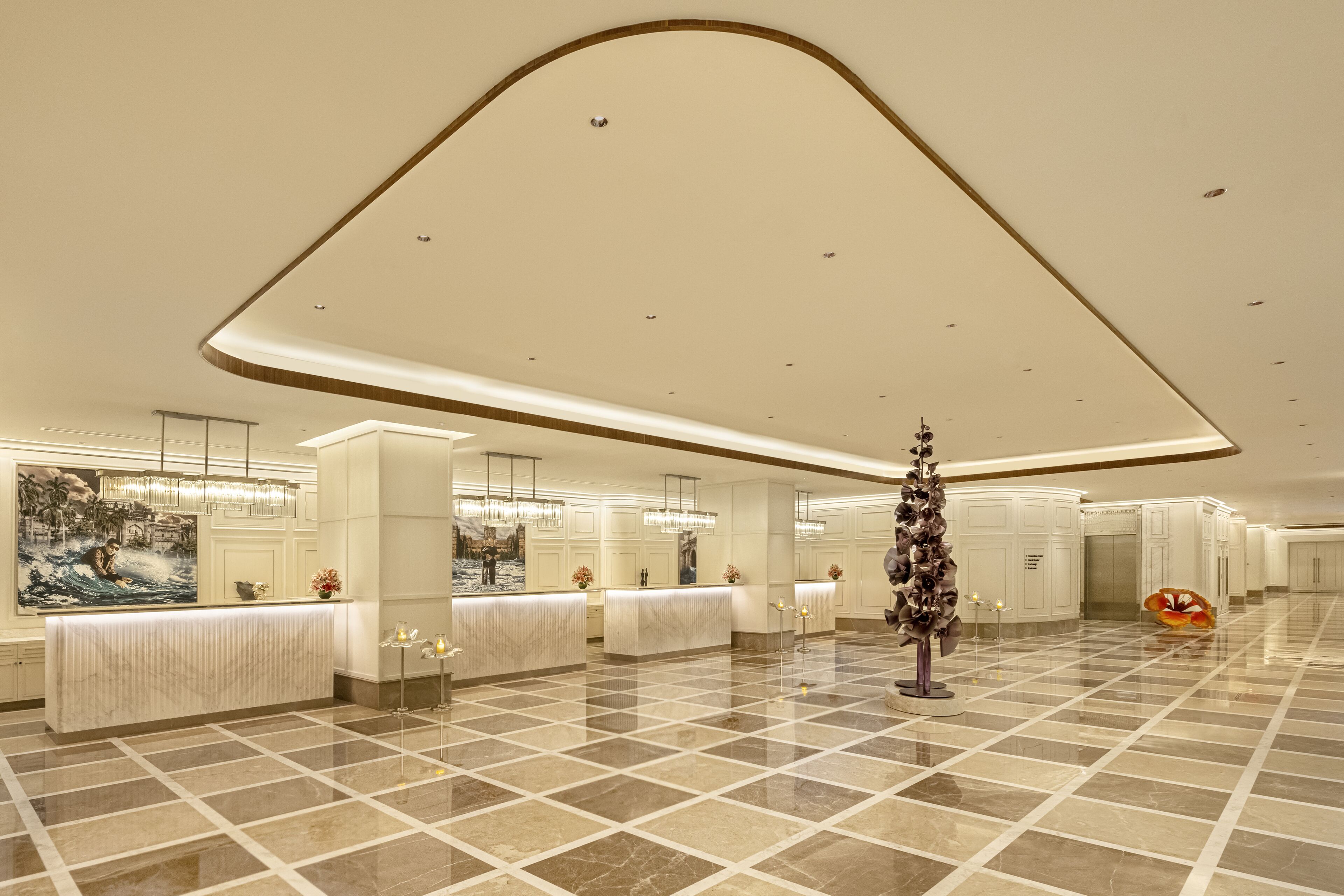 A spacious lobby with a marble floor, a reception desk, and a large painting on the wall.