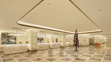 A spacious lobby with a marble floor, a reception desk, and a large painting on the wall.