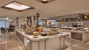 Amplia y luminosa cocina con suelo de mármol, que incluye una isla central con diversos alimentos y un reloj grande en la pared.