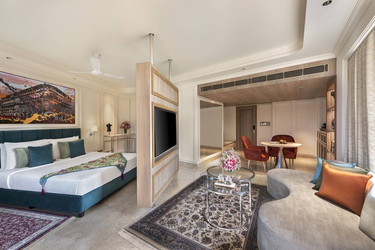 Une chambre d’hôtel comprenant un lit, une télévision, un canapé, une table basse et un coin repas.