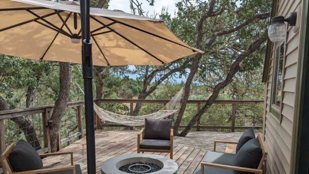 A wooden deck with outdoor furniture, a fire pit, and a hammock.