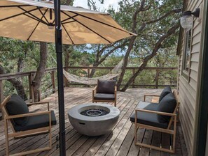 Eine Holzterrasse mit Gartenmöbeln, einer Feuerstelle und einer Hängematte.