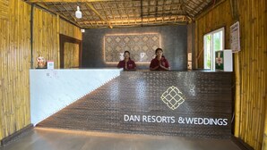 Un área de recepción con detalles de bambú, dos recepcionistas, una pared decorativa y un letrero de Dan Resorts & Weddings.