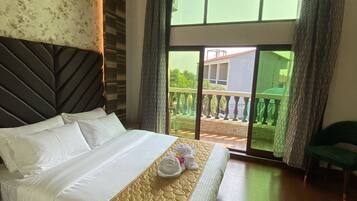 A hotel room with a large bed, a headboard, a window with curtains, and a view of the outside balcony.