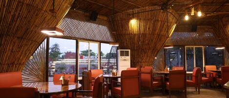 Un restaurant avec un plafond en bambou, des chaises et des tables orange.