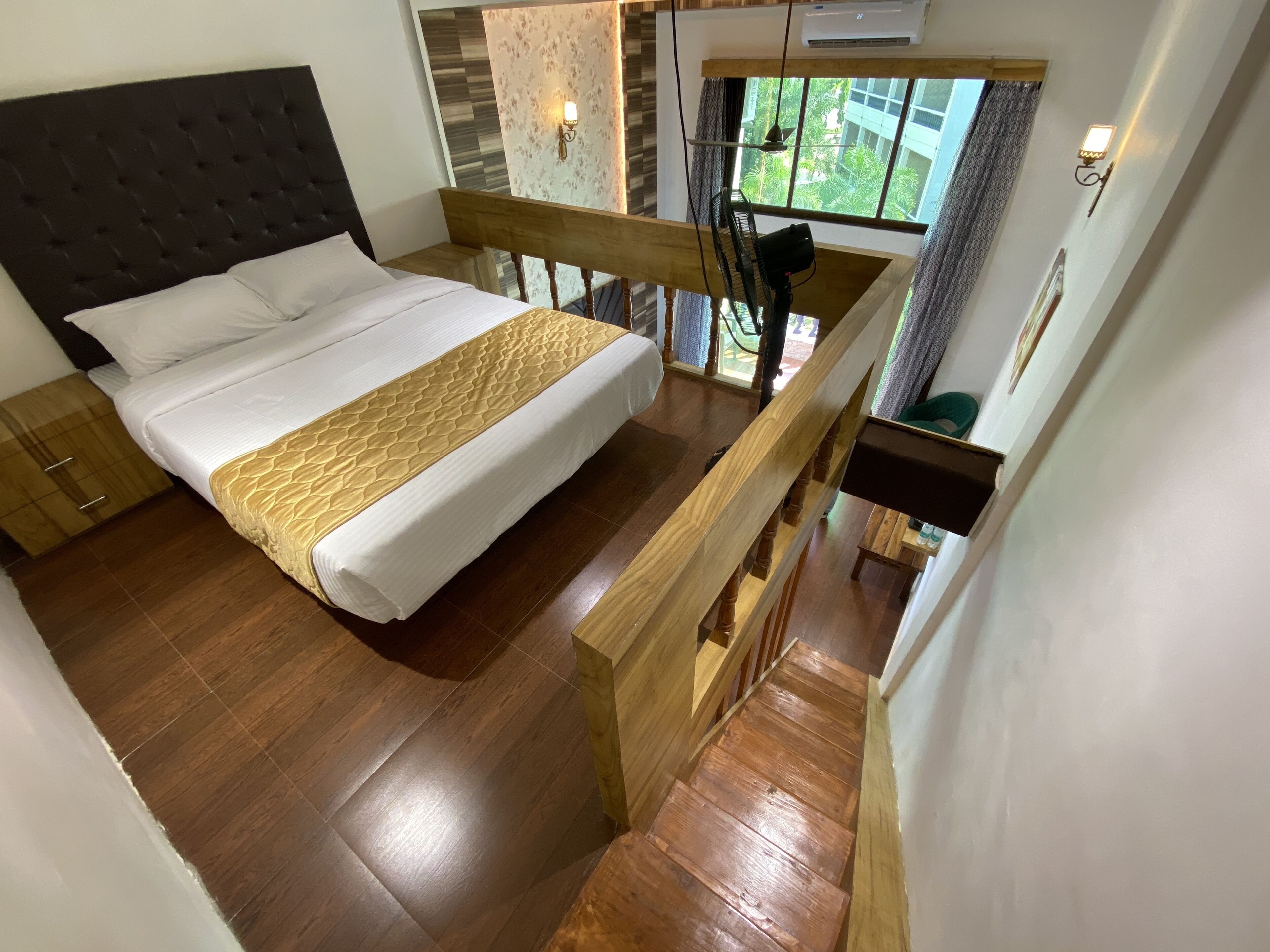 Una camera da letto con un letto, pavimento in legno e una scala.
