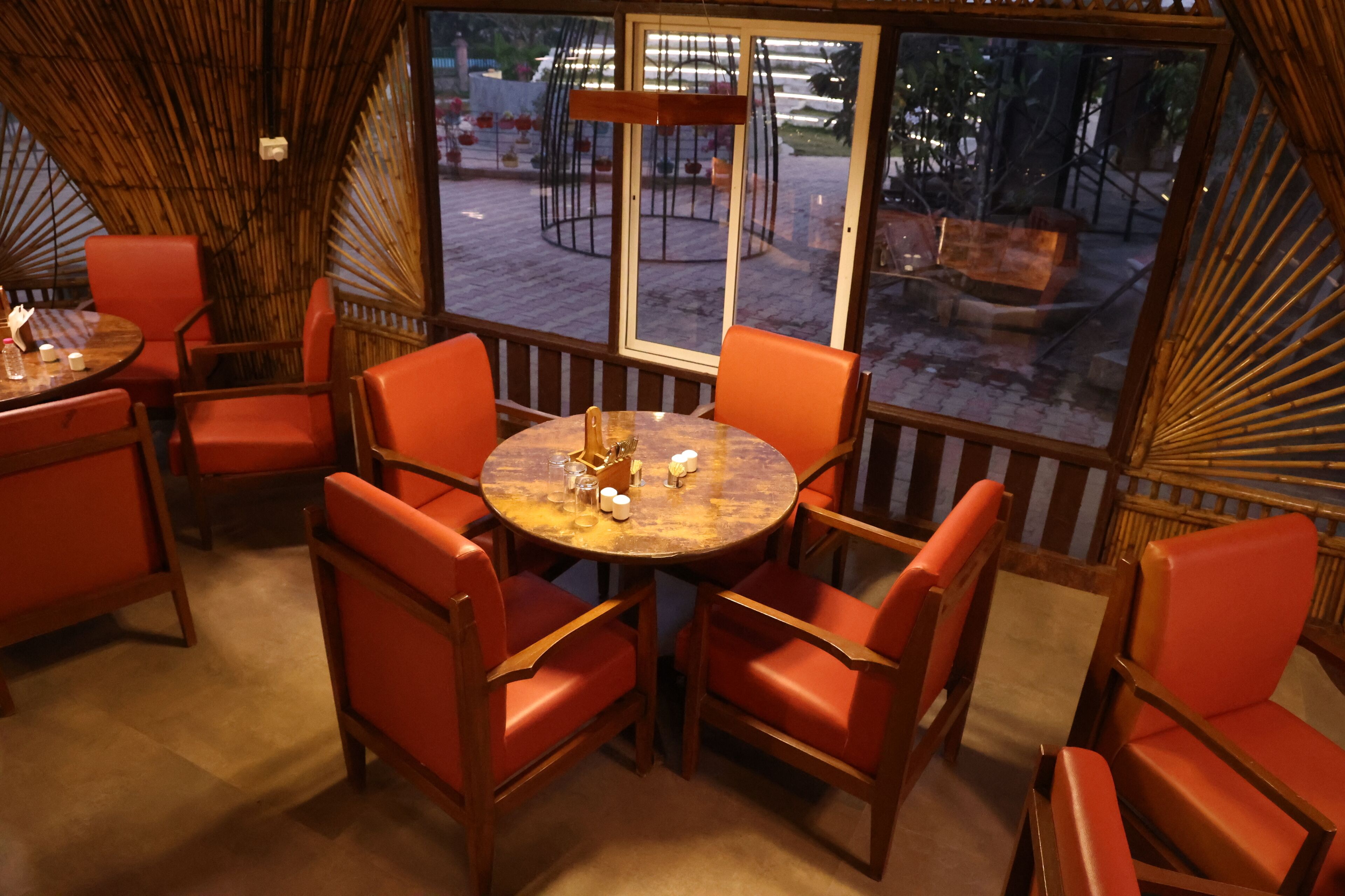 Un espace repas accueillant avec des tables rondes et des chaises orange, de grandes fenêtres donnant sur l’espace extérieur.