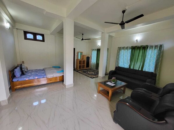 A spacious living area with a sofa, a coffee table, and a bed with a blue mattress.