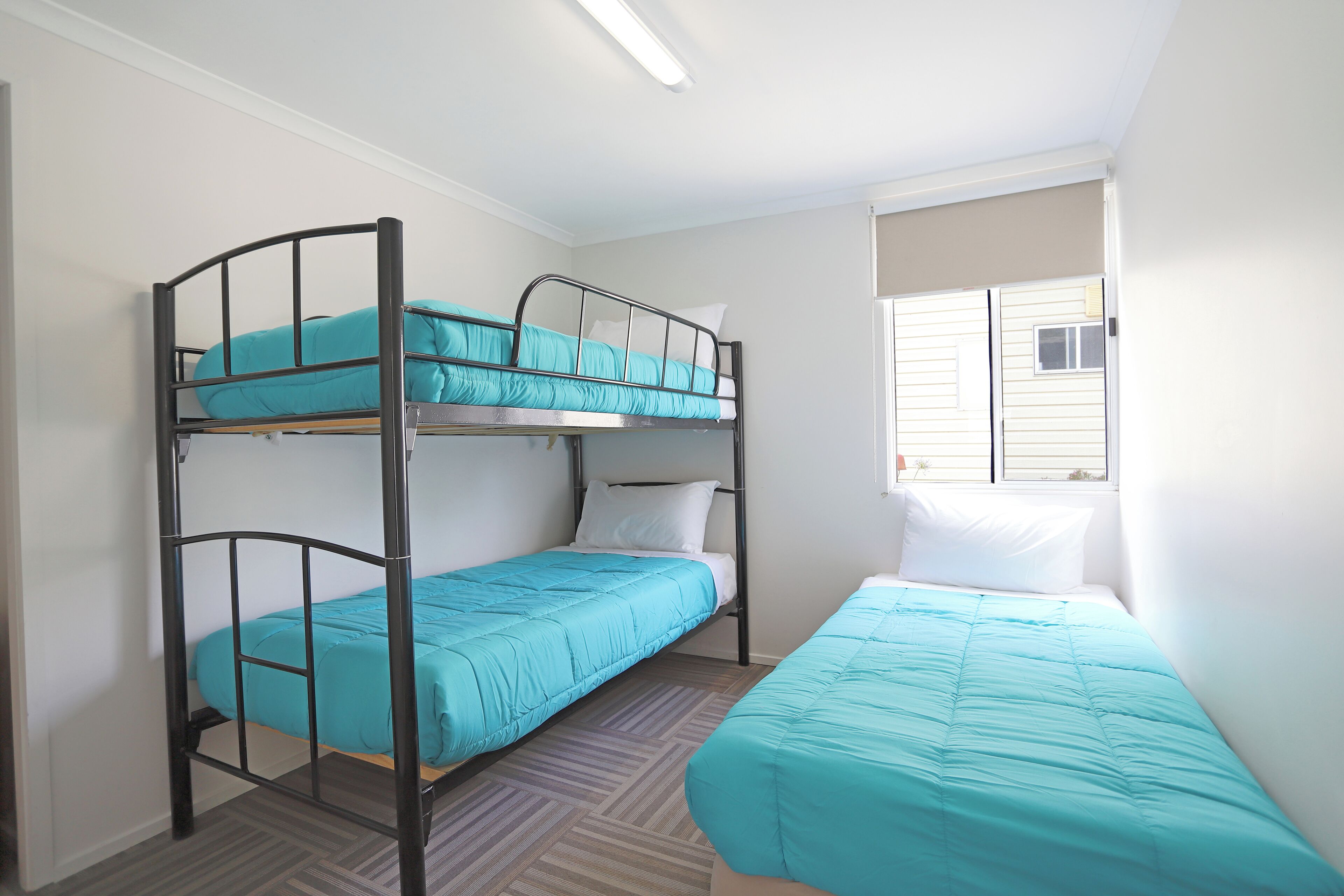 A bunk bed room with a window and a door.