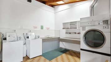 Un lavadero con dos lavadoras, un secador y un lavabo.