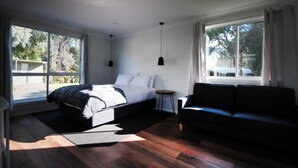 A modern bedroom with a large bed, a black sofa, and a small side table. - Wonthaggi Park Lane Holiday Park (Wonthaggi)