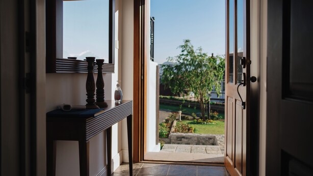 A doorway leading to a garden with a view of trees and a clear sky.