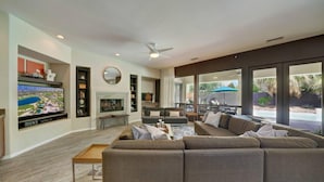 A modern living room with a large sectional sofa, a flat-screen TV, and a fireplace. - Summer Early Late Access Private Pool Spa (Indio)