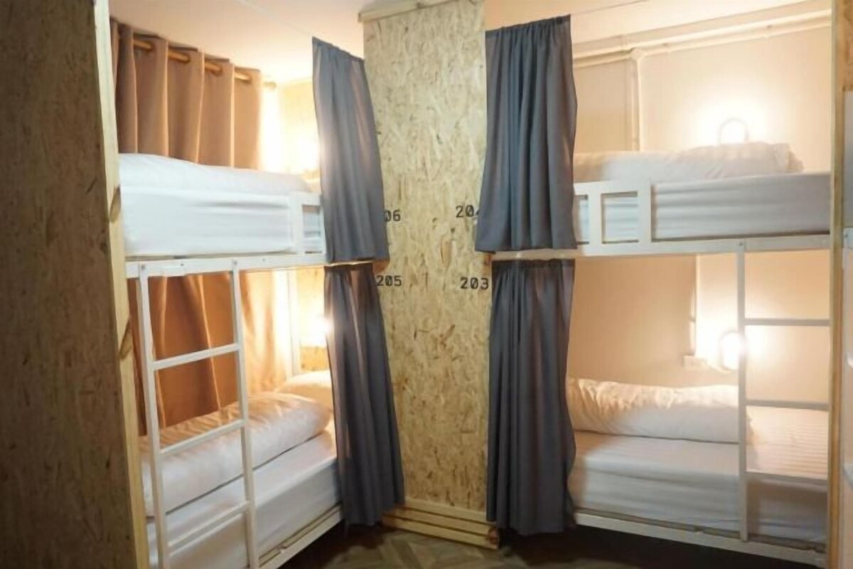 Une chambre avec des lits superposés, des rideaux et une fenêtre.