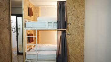 A bunk bed room with a wooden wall and a curtain.