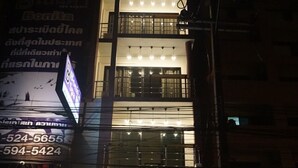 Um hostel com estrutura em dois andares, várias janelas e uma entrada convidativa com uma placa.