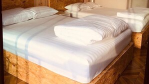 Quarto de hotel com duas camas, cabeceiras de madeira e luminárias fixadas na parede.