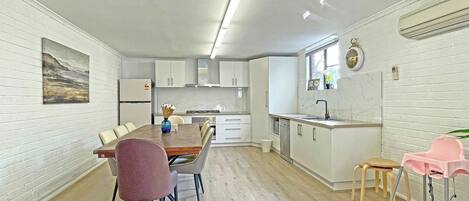 A modern kitchen with white cabinetry, a dining area with a wooden table and chairs, and a small island with a sink.