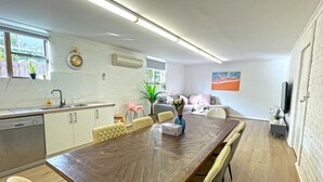 A modern kitchen with white cabinets, a wooden dining table, and a built-in oven.