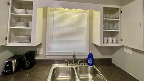 A compact kitchen with a double sink, a toaster, and cabinets above the sink.