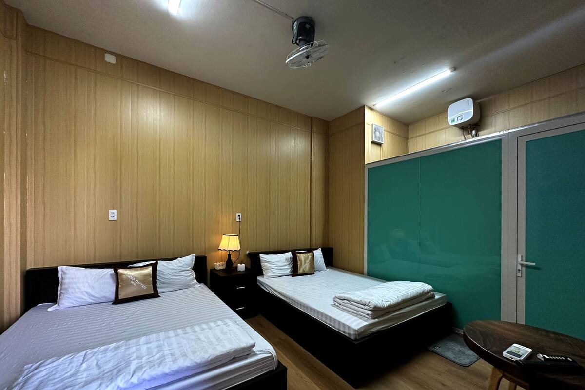 Habitación de hotel con dos camas, un escritorio y un armario verde.