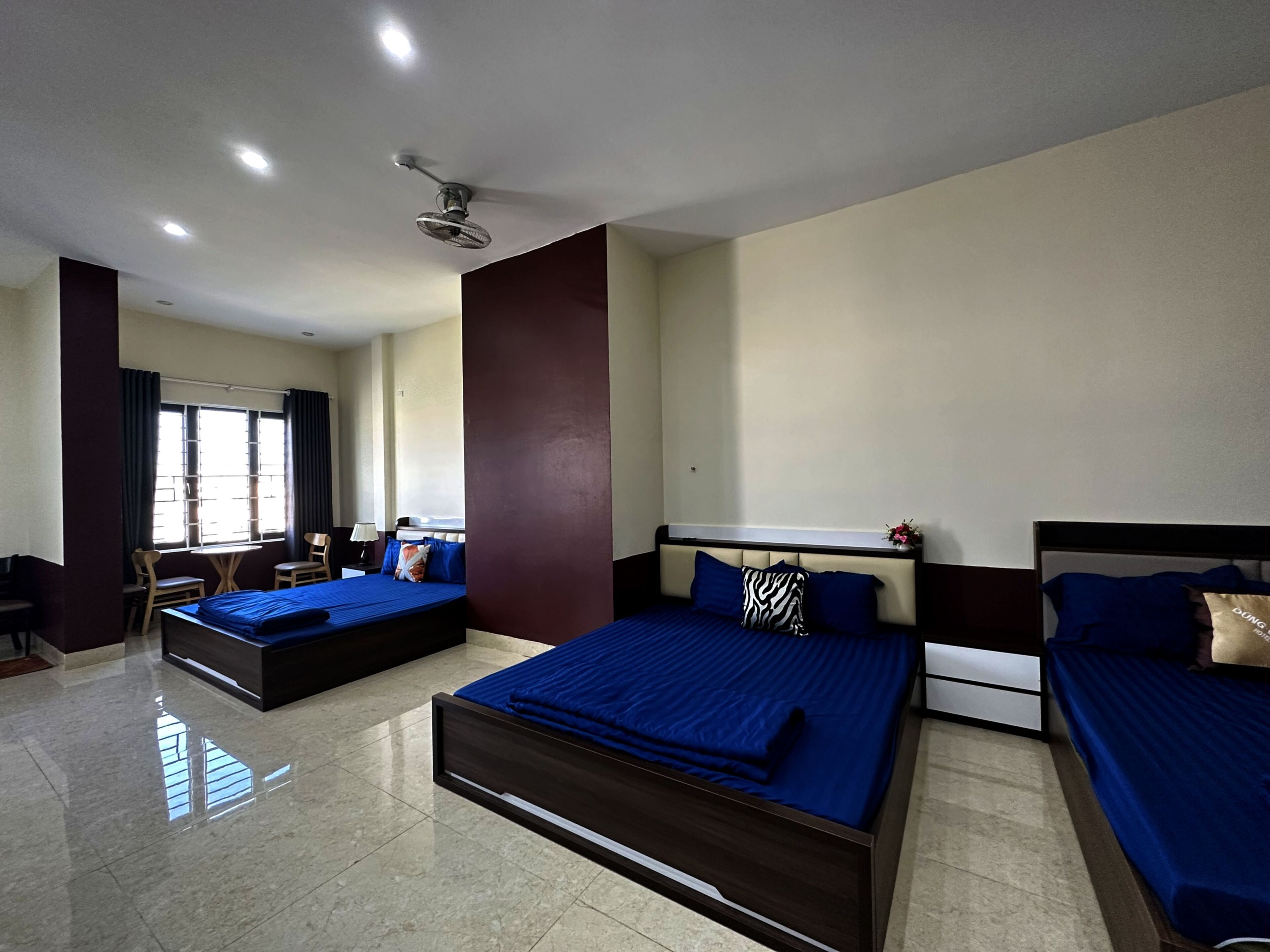 A hotel room with two beds, a desk, and a chair.