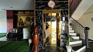 Eine Hotelhalle mit einer Marmortreppe, einer Holzvase und einer Wanduhr.