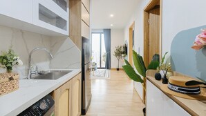 A modern kitchen with a stainless steel sink, wooden cabinets, and a built-in oven. - Crescendo Urban Stay (Hanoi)