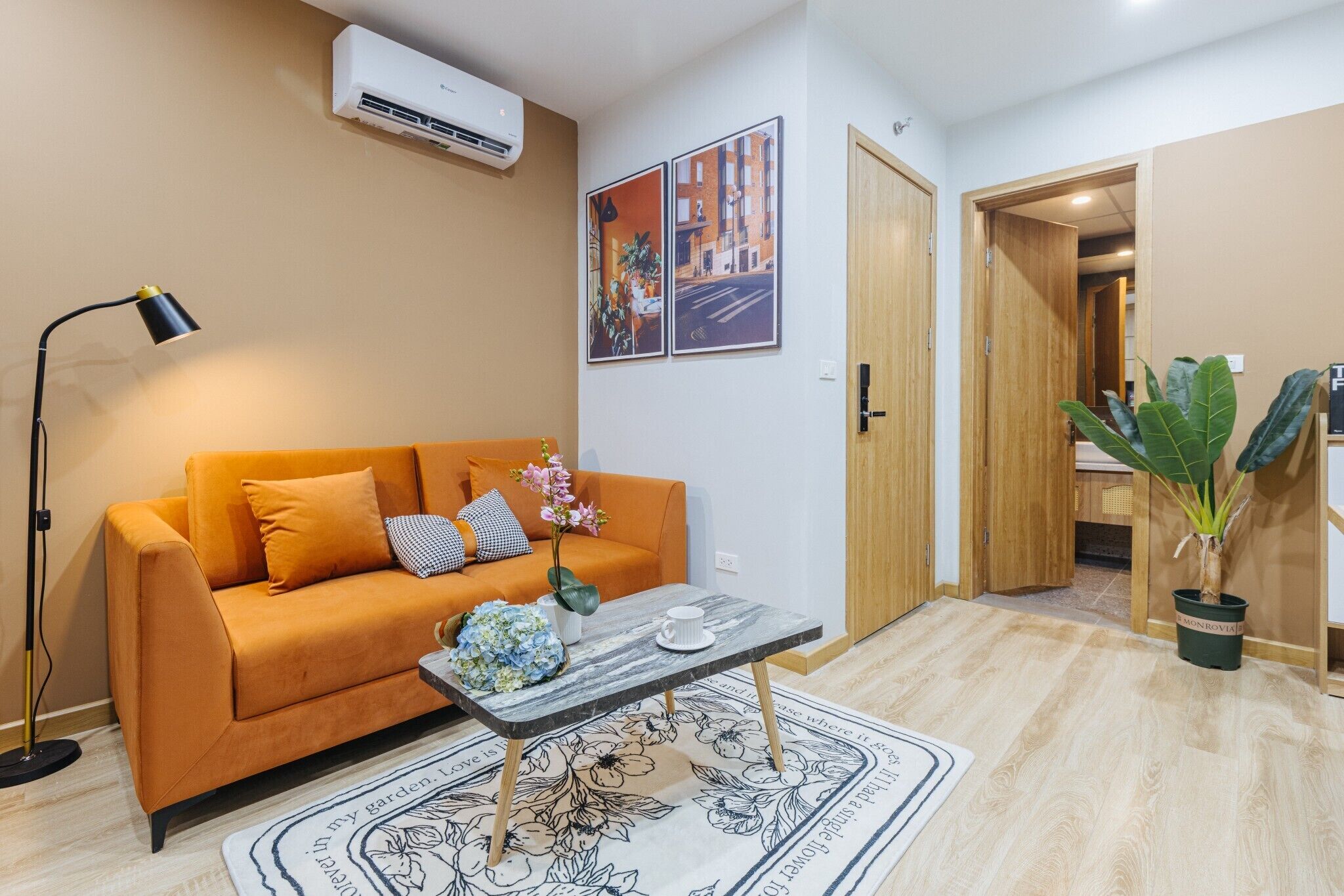 Un salon avec un canapé orange, une table basse, un lampadaire et une plante en pot.