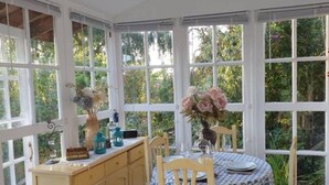 A conservatory with a table set for dining, surrounded by large windows offering a view of greenery. - The Stables w/Hot tub, amazing views, English Bicknor Forest of Dean (Coleford)