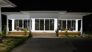 A modern house with a covered porch, large windows, and outdoor seating. - MacMillan's Holiday Villas await you offering a modern living space (Grand Anse Praslin)