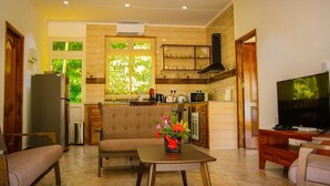 A modern kitchen with a built-in oven, microwave, and coffee maker. There is a dining area with a sofa and a table with a vase of flowers. - MacMillan's Holiday Villas await you offering a modern living space (Grand Anse Praslin)