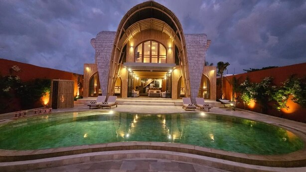 Une villa luxueuse dotée d’une grande piscine, d’une entrée imposante et d’un intérieur bien éclairé.