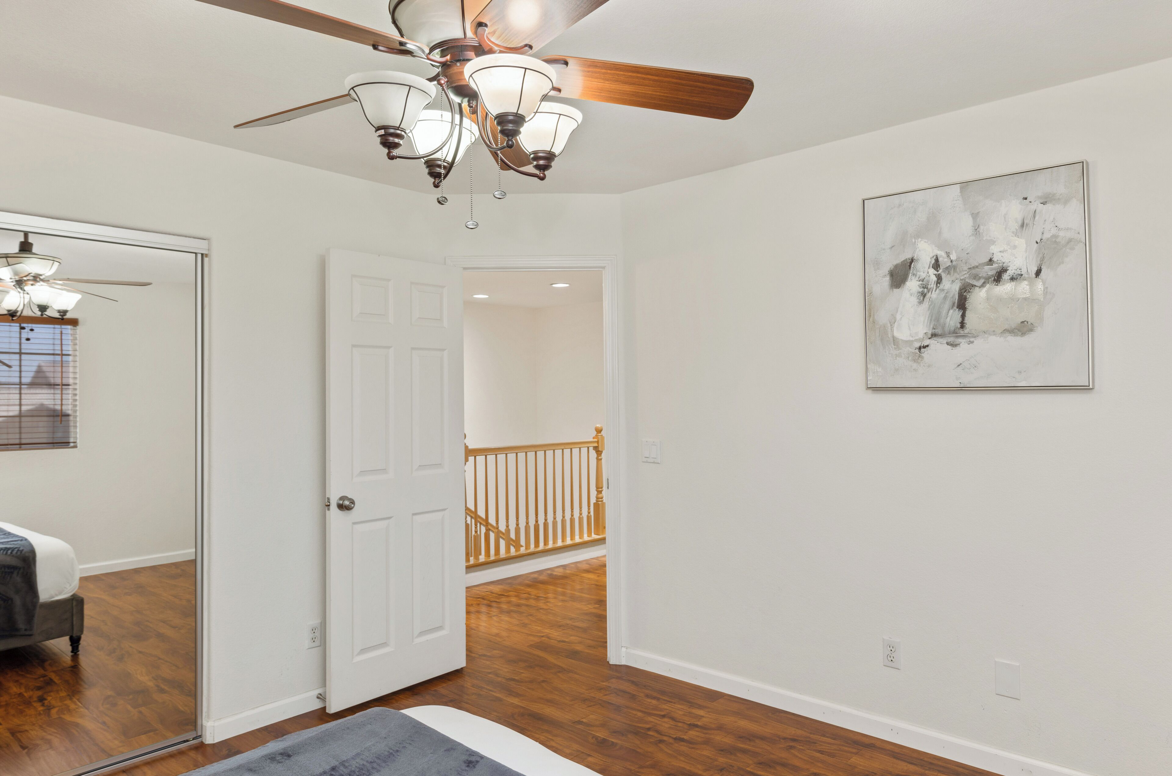 A hallway with a ceiling fan, a door leading to another room, and a staircase.