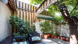 Eine Terrasse mit Gartenmöbeln, Blumentöpfen und einem Baum.